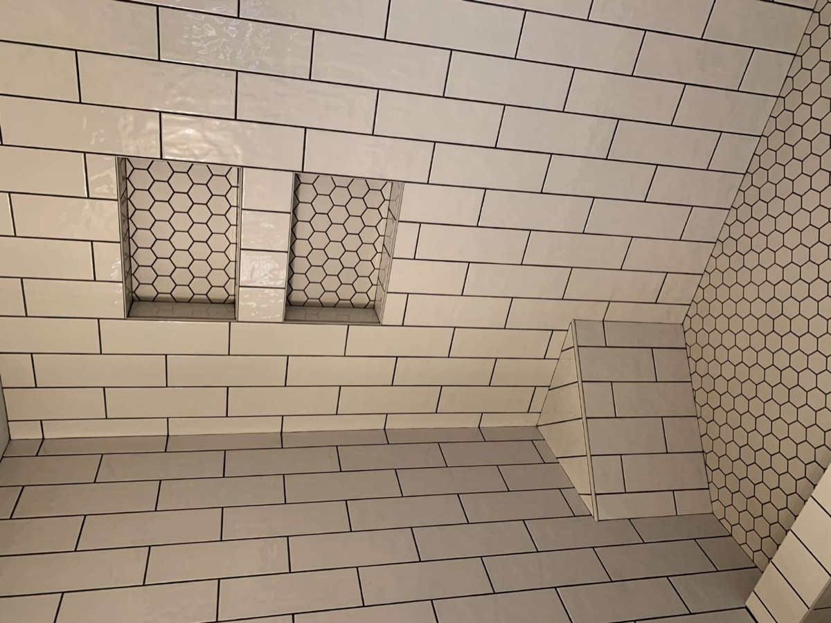 Subway-tile shower with hexagon-tiled niches