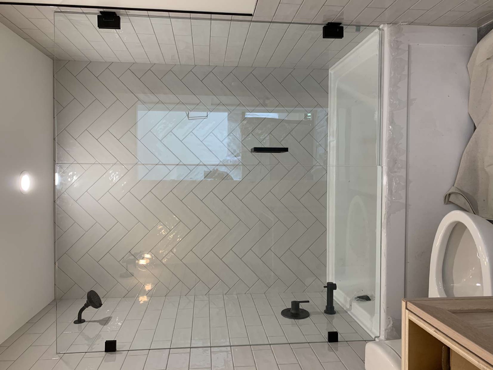 Hand-set herringbone tile walk-in shower with frameless glass