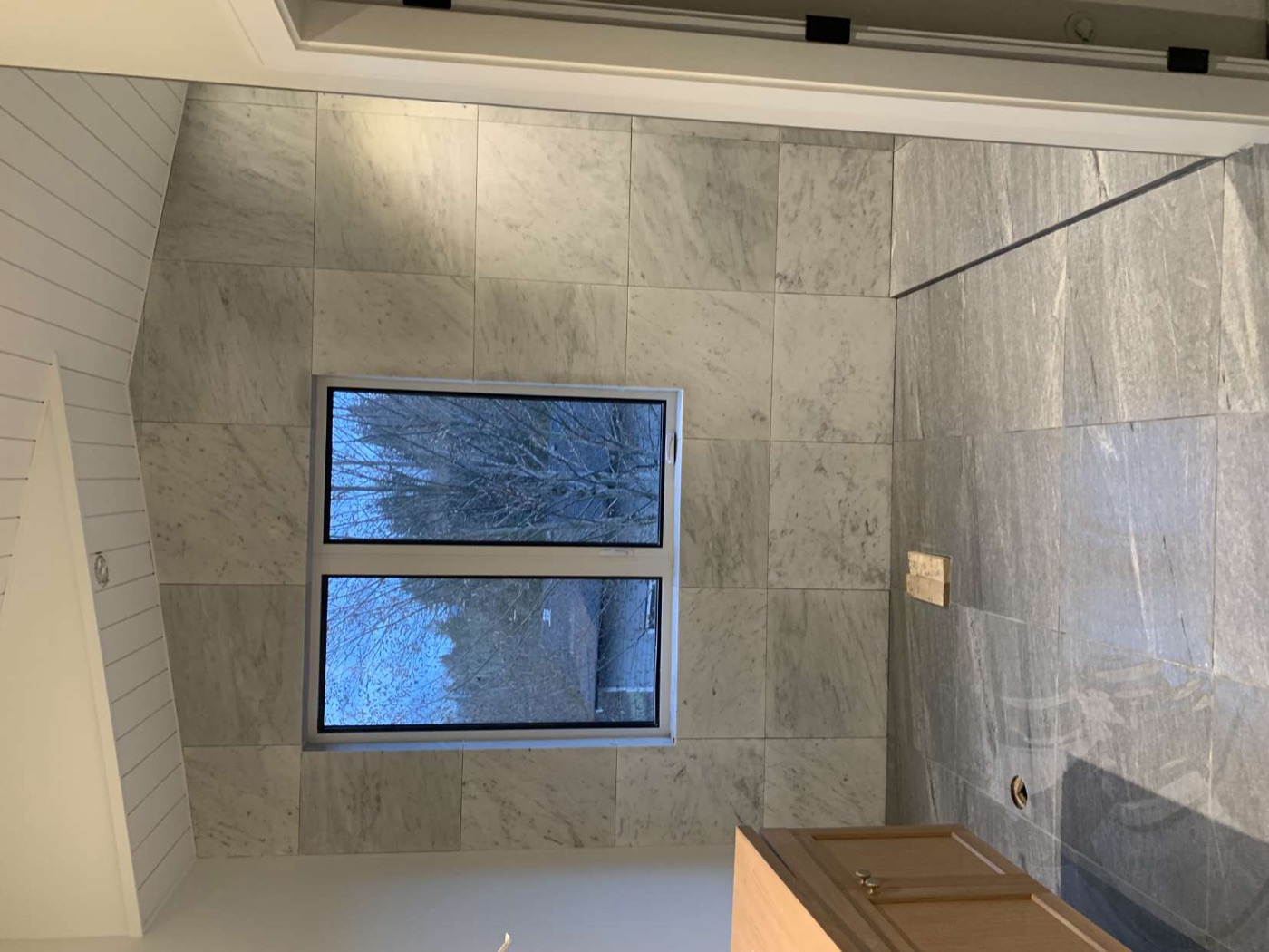 Marble ensuite bathroom with framed window and floor-to-ceiling tile