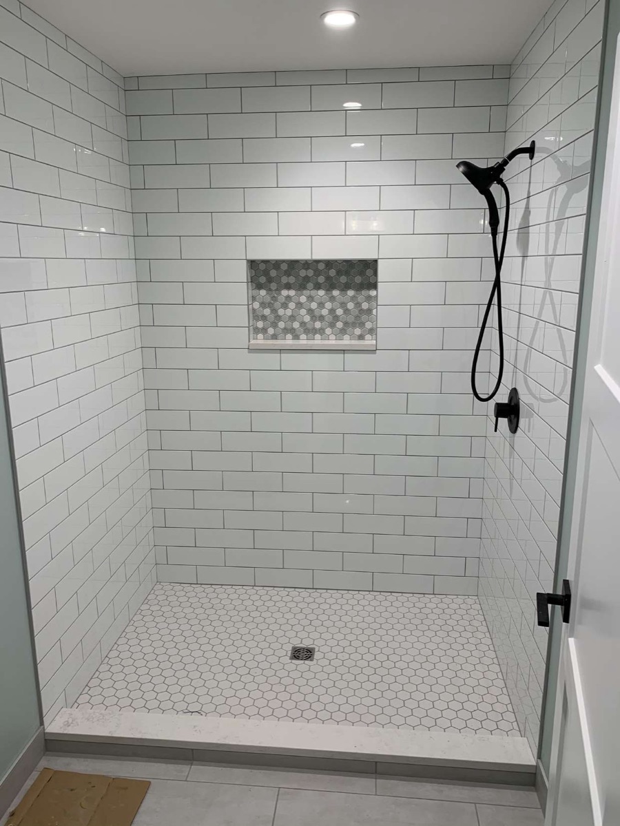 Subway-tile walk-in shower with recessed niche and mosaic floor
